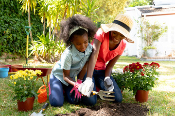 African American girl and her mother planting flowers.