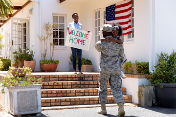 African American woman and her daughter standing  welcoming an African American soldier