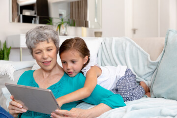 Senior Caucasian woman using a tablet at home with her granddaughter