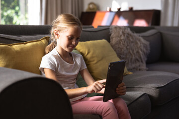 Obraz premium Portrait of a Caucasian girl using a digital tablet on a couch