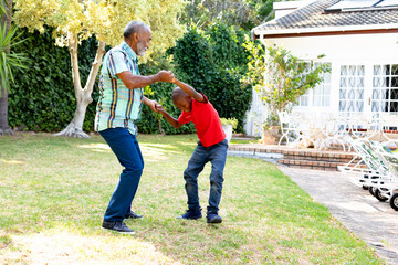 Senior African American man and his grandson spending time together in their garden on a sunny day