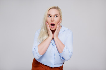 portrait of surprised beautiful plus size blonde woman over gray background