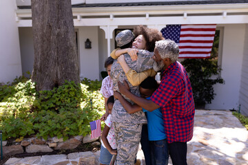Multi-generation mixed race family welcoming an African American man wearing military uniform