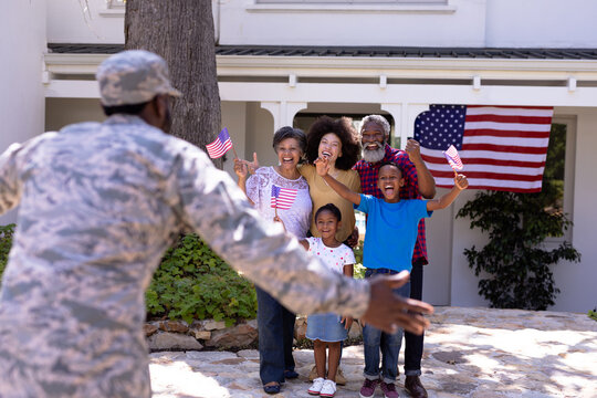 Multi-generation mixed race family welcoming an African American man wearing military uniform - Powered by Adobe