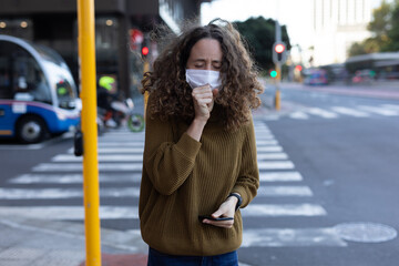 Caucasian woman wearing a protective mask and coughing out in the streets