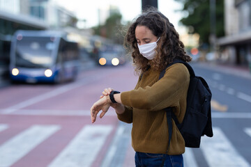 Caucasian woman wearing a protective mask and checking her watch