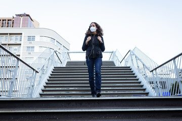Caucasian woman wearing a protective mask and walking down the stairs