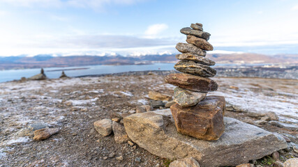Glücksturm aus Steinen, im Hintergrund Tromsö, Finnmark, Norwegen