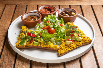 humus with turmeric over ciabatta bread with avocado and dry tomato on top. Served with green salad...