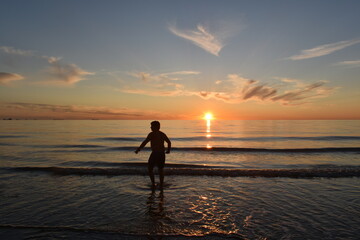 Katwijk aan Zee / The Netherland - June 20 2020: Local sports fishermen are walking in the sea, trawling their fishnet along the beach fishing for sole, in the evening at sun set. 