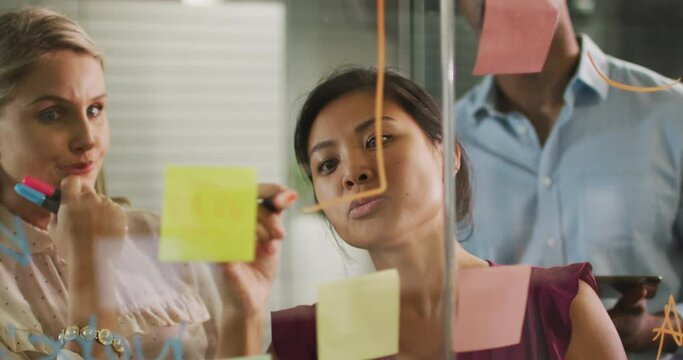 Professional businesspeople discussing while writing on the whiteboard in modern office in slow moti