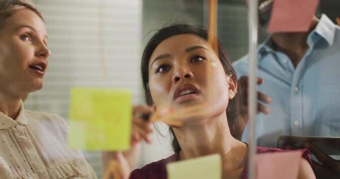 Professional businesspeople discussing while writing on the whiteboard in modern office in slow moti