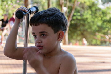 7 year old child sitting next to his scooter, moving his left hand.