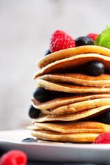 Pancakes with blueberries, raspberries, mint and honey for a breakfast