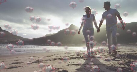 Digital composite video of Covid-19 cells moving against couple walking on the beach in background - Powered by Adobe