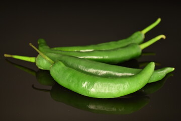 Green chili pepper, close-up, on a black background.