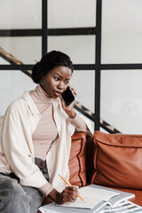 Serious young african woman talking by mobile phone