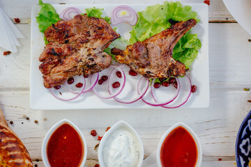 Top view of barbecue ribs with sauces over the white plate.
