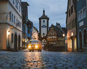 Orange Transporter T2 on background of Rothenburg ob der Tauber, Christmas decorated city of Franconia, Bavaria in Germany.