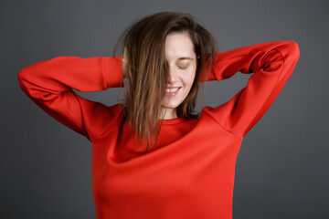 cheerful beautiful young woman in a red jacket. brunette on a dark gray background in the Studio. a smile on her face and her hair covered half her face.