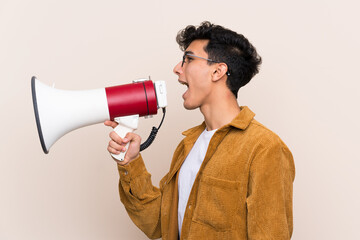 Young Argentinian man over isolated background shouting through a megaphone