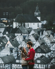 Stylish hipster family couple embracing spending time together. Young couple standing on background of historic houses in Freudenberg, Germany. Travel Lifestyle concept