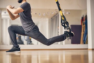 Sporty young male is doing lunge indoors