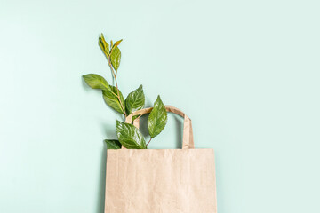 Recycled brown paper shopping bag with handle and green branches leaves isolated on white background. Zero waste concept. Top view, flat lay, copy space.