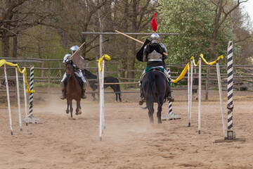 A knight in vintage armor of the 15th century rides a horse across a field for a tournament
