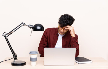 Young Argentinian man in a table with a laptop in his workplace