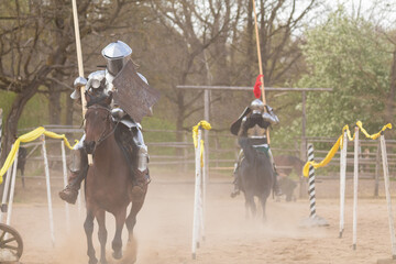 A knight in vintage armor of the 15th century rides a horse across a field for a tournament
