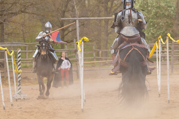 A knight in vintage armor of the 15th century rides a horse across a field for a tournament