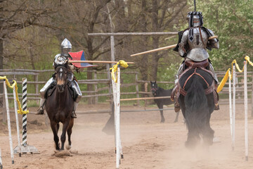 A knight in vintage armor of the 15th century rides a horse across a field for a tournament