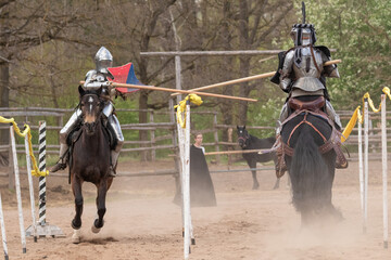 A knight in vintage armor of the 15th century rides a horse across a field for a tournament
