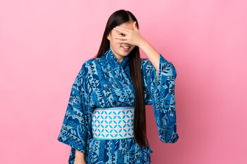Young Chinese girl wearing kimono over isolated background covering eyes by hands and smiling