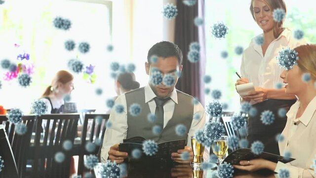 Animation of macro Covid-19 cells floating o ver Caucasian couple drinking and ordering to a waitres