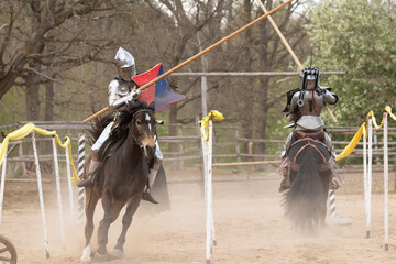 A knight in vintage armor of the 15th century rides a horse across a field for a tournament