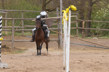 A knight in vintage armor of the 15th century rides a horse across a field for a tournament