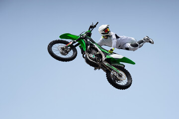 Ricer in a white protective uniform and helmet shares a stunt in the air on a motorcycle. jump and...
