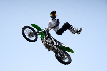 stunt racer in protective uniform and helmet does a dangerous stunt in the air on a motorcycle. jump and flight on a motorcycle. extreme sport. motor freestyle
