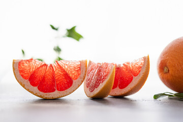 Juicy sliced grapefruit with green leafs on white background. Side view, close up. healthy food, nutrition, dieting. Natural cosmetics