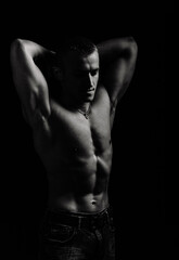 Fototapeta premium Athletic man's torso. Unrecognizable male fitness model show naked muscular body. Strong muscles and biceps. Studio shot on black background, monochrome, black and white. Bodybuilding concept