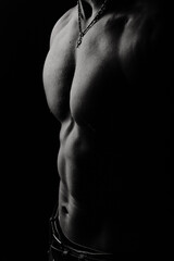 Athletic man's torso. Unrecognizable male fitness model show naked muscular body. Strong muscles and biceps. Studio shot on black background, monochrome, black and white. Bodybuilding concept