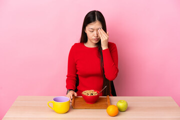 Young Chinese girl  having breakfast in a table with headache