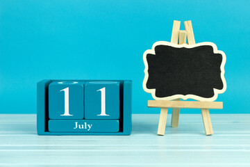wooden calendar with the date of June 11 and an easel on a blue background, place for text, World...