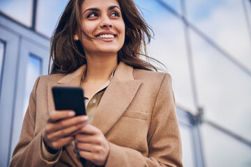 Attractive businesswoman looking happy with her gadget