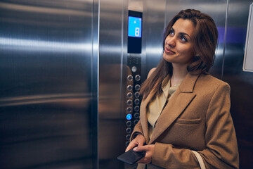 Successful business lady going down in elevator - obrazy, fototapety, plakaty