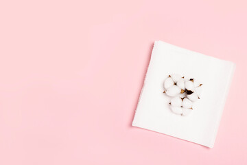 Paper towels and cotton flowers on a pink background. Concept is 100% natural product, delicate and soft. Flat lay, top view. Banner
