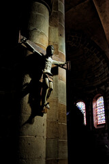 Statue of Jesus Christ crucifixion on a brick wall background in a dark church with stained glass...