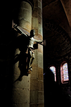 Statue of Jesus Christ crucifixion on a brick wall background in a dark church with stained glass windows. France